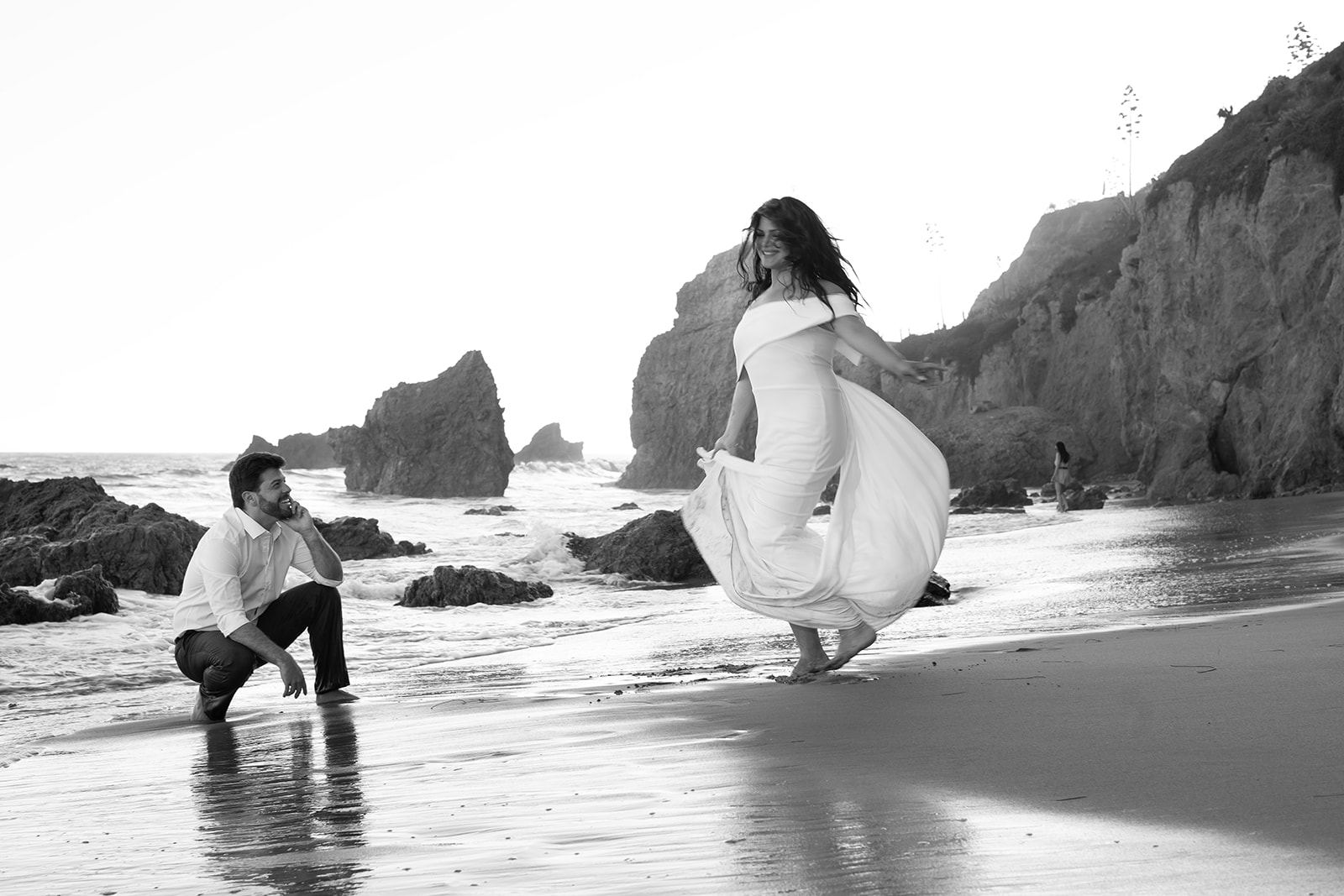 Cam dancing barefoot on the beach while Sari watches, smiling