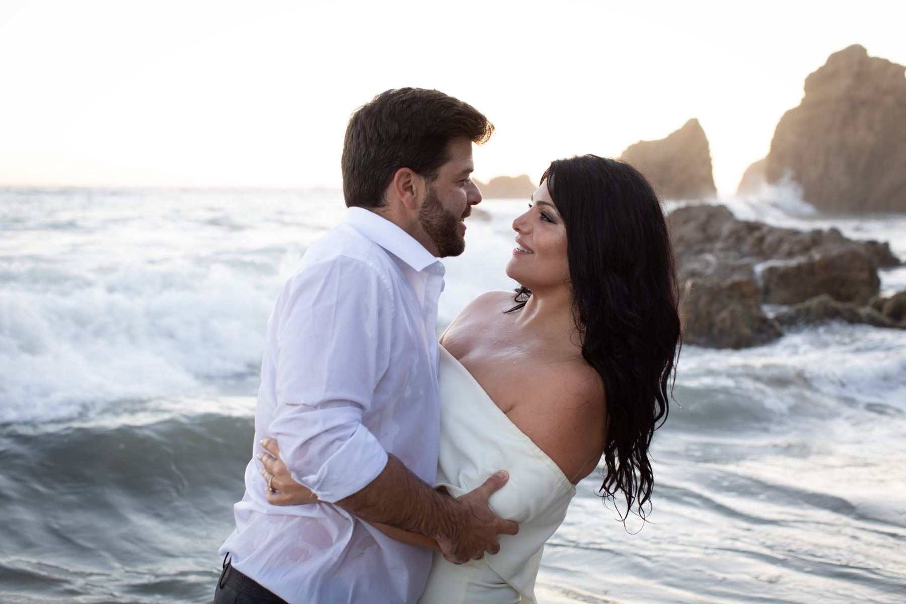Cam and Sari facing each other in the surf at sunset